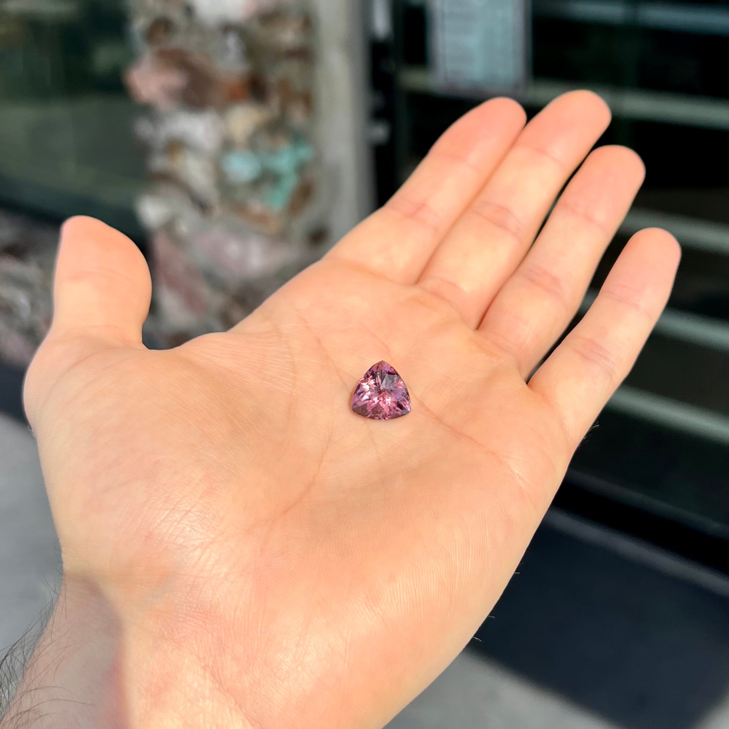 A loose, checkerboard trillion cut purple tourmaline gemstone.