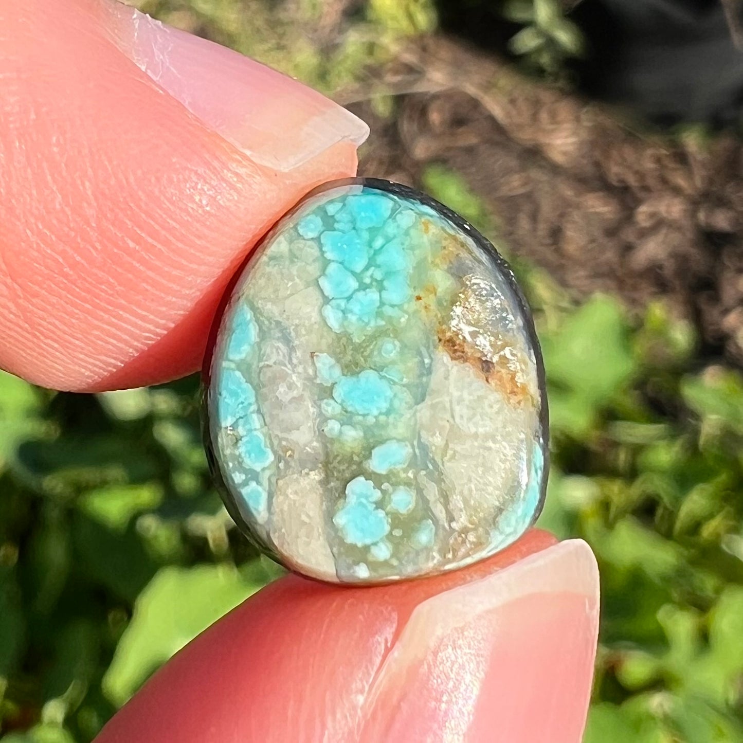 A loose, freeform pear shaped cabochon cut Valley Blue turquoise stone from Lander County, Nevada.  The stone is blue and green with quartz inclusions.