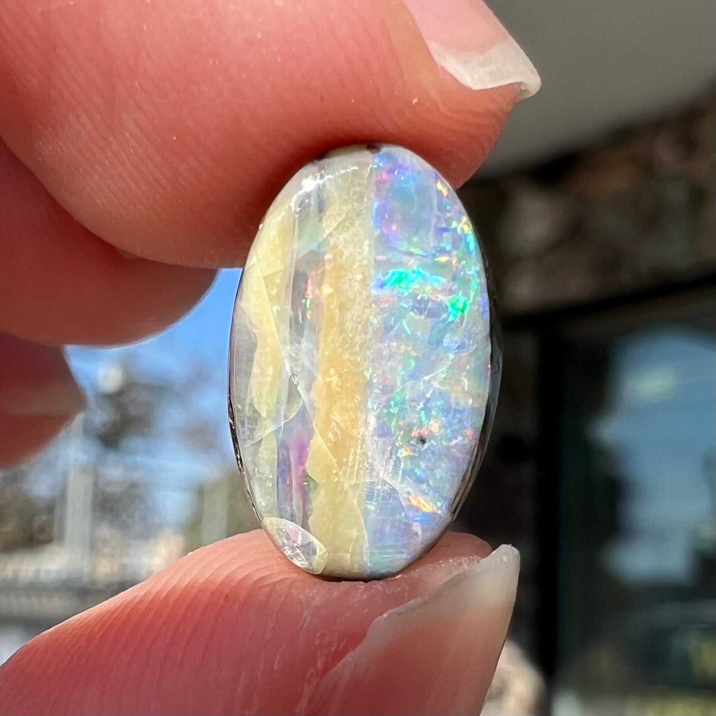 An oval cabochon cut boulder opal from Quilpie, Australia.  The opal has multicolor color play.