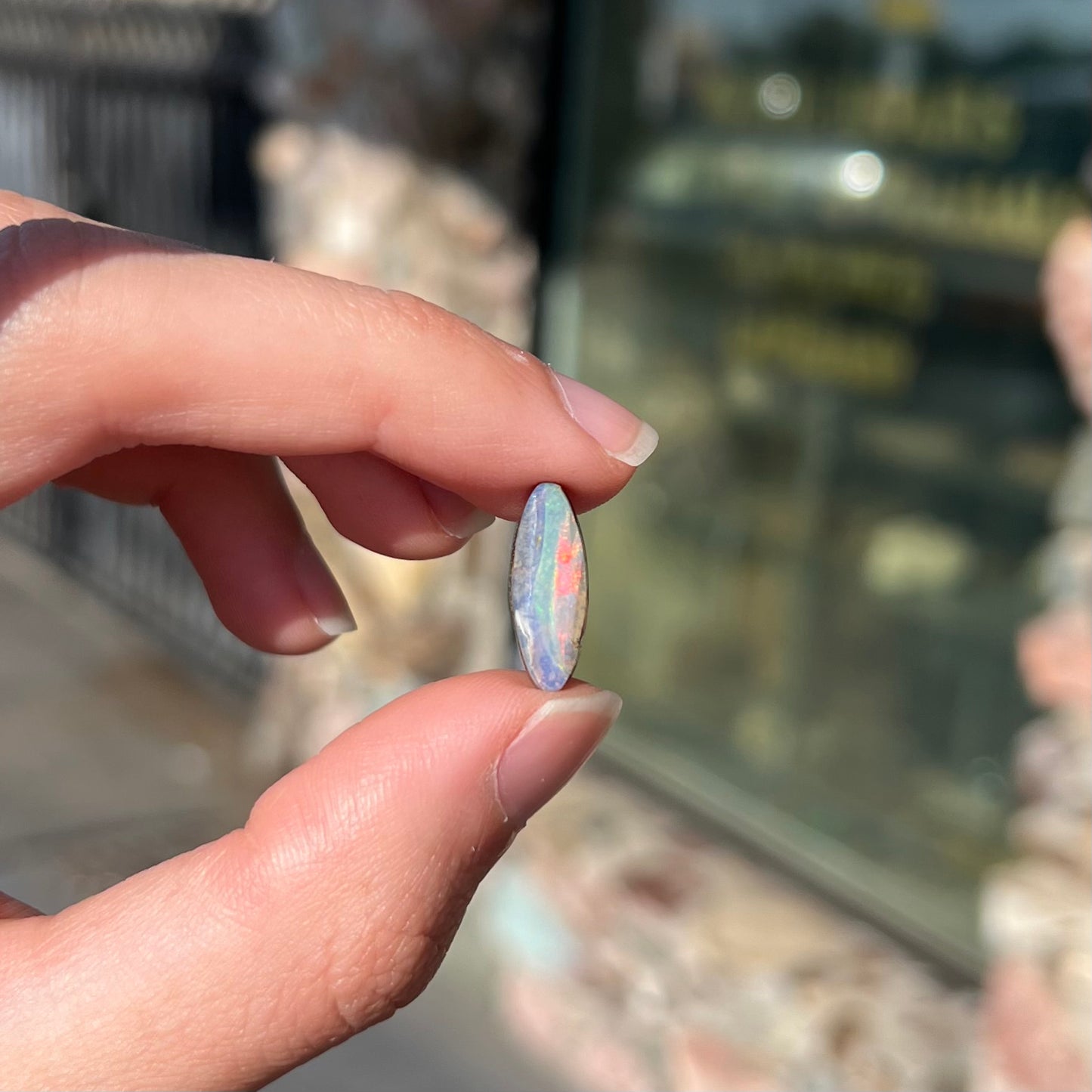 A loose, marquise cut boulder opal from Quilpie, Australia.  The opal has green and red wave patterns.