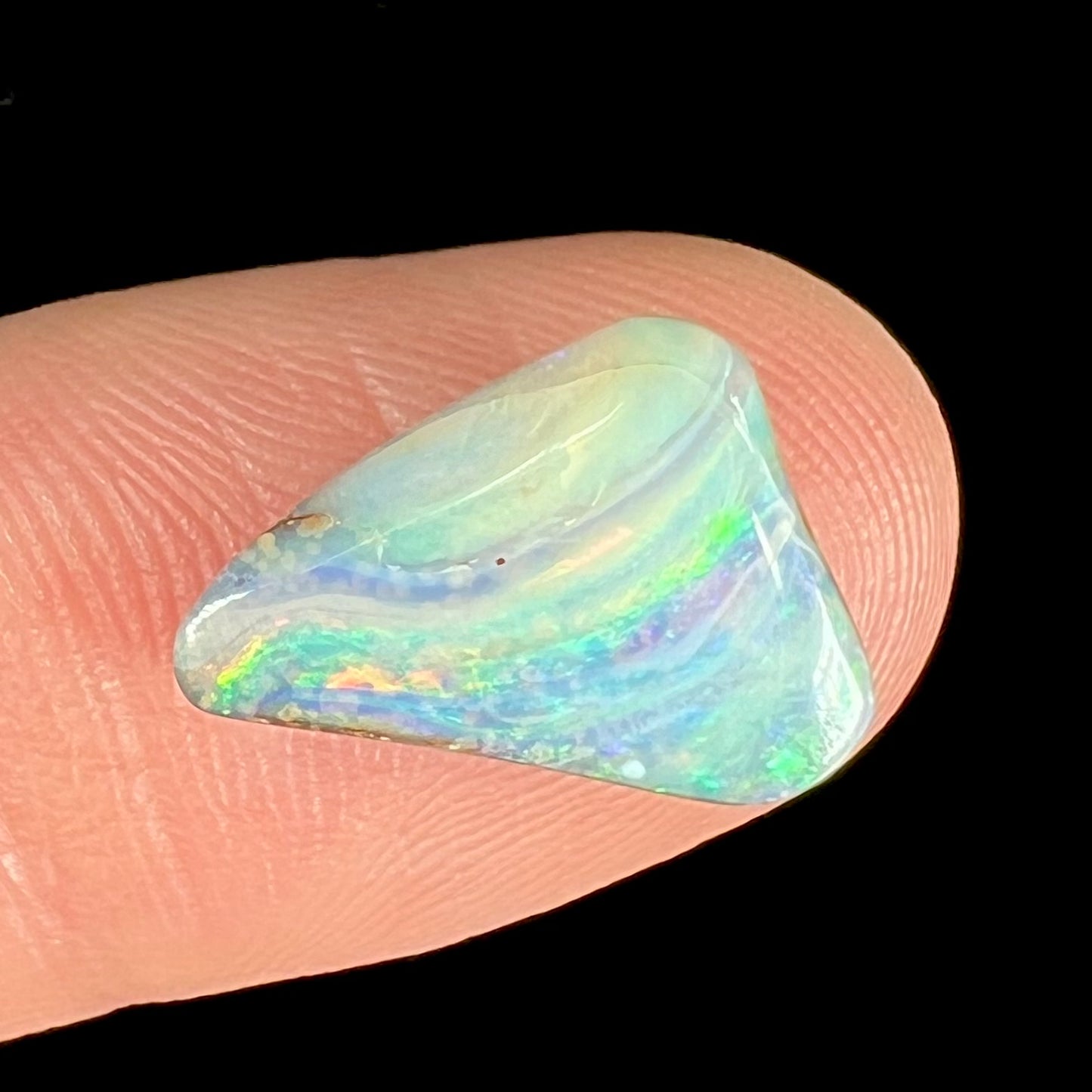 A loose, freeform boulder opal stone from Quilpie, Australia.  The opal has a fissure inclusion.