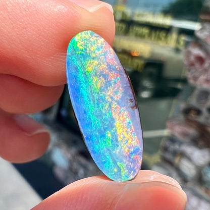 A loose, oval cut rainbow boulder opal gemstone.