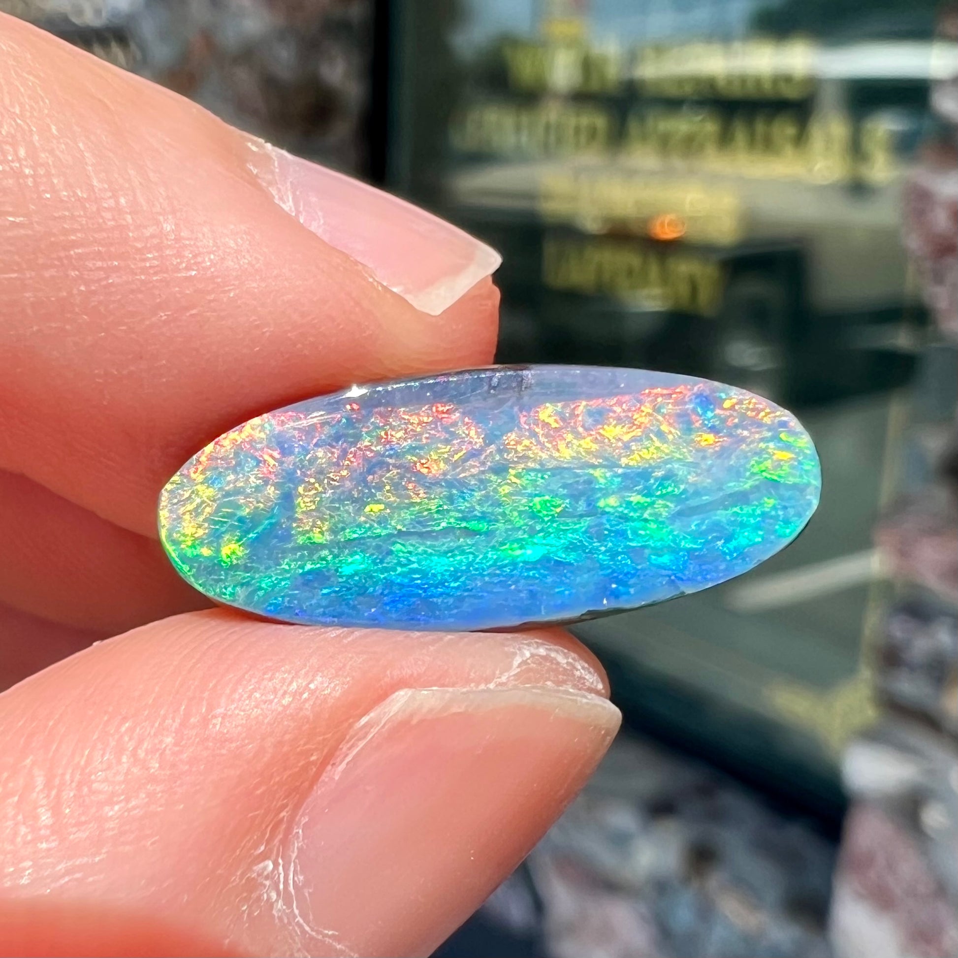 A loose, oval cut rainbow boulder opal gemstone.