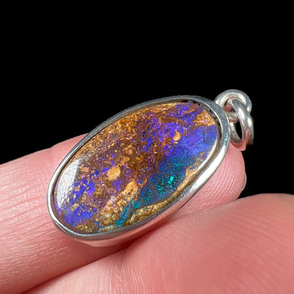 A handmade sterling silver pendant bezel set with an oval cut pipe boulder opal stone.