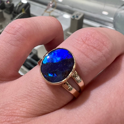 A ladies' split shank natural, Lightning Ridge, Australian black opal solitaire ring in yellow gold.