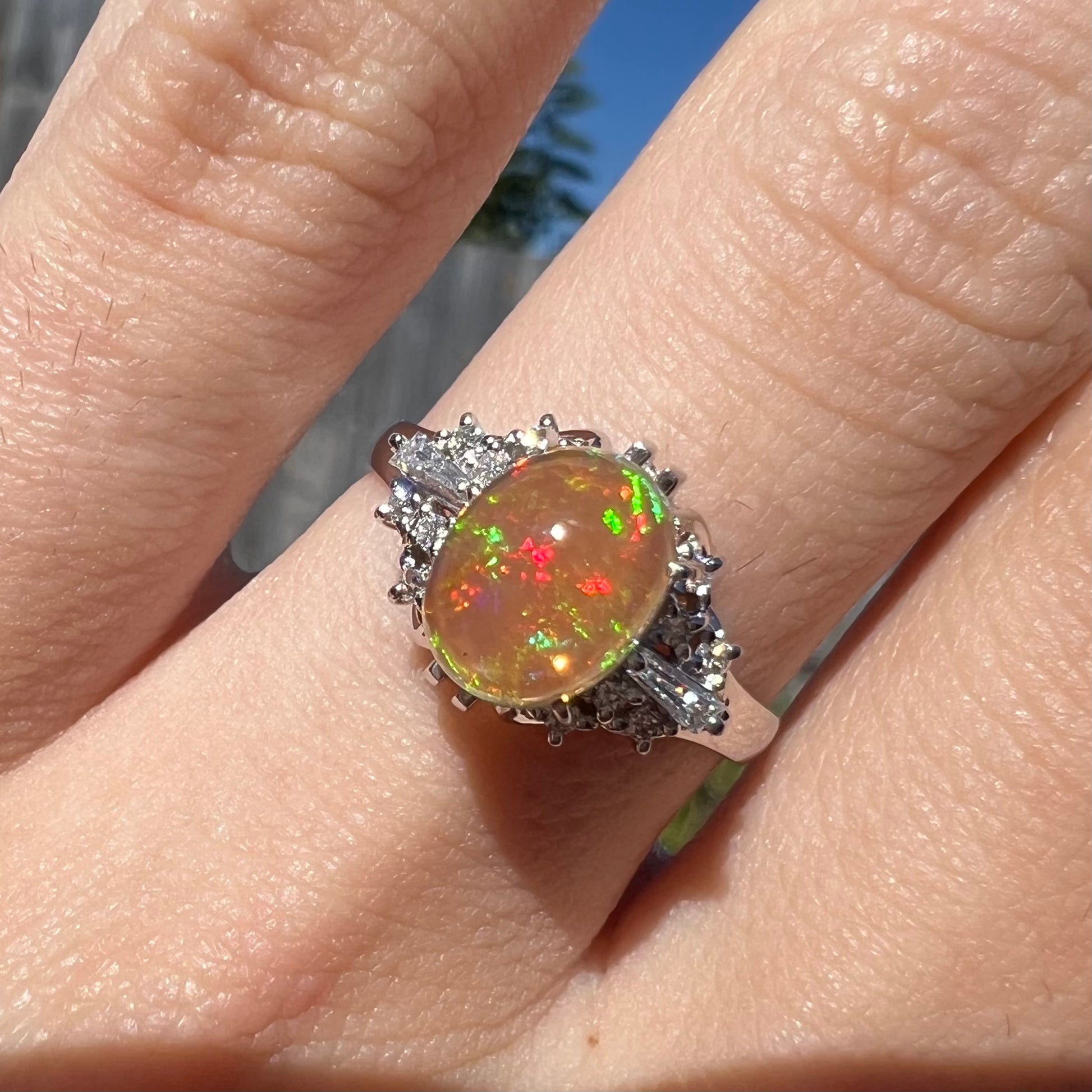 A platinum filigree ring mounted with a high-domed Mexican fire opal and baguette cut diamond accents.