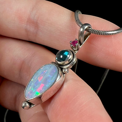 A sterling silver necklace shaped like a child, mounted with an opal doublet, a ruby, and a blue piece of glass.