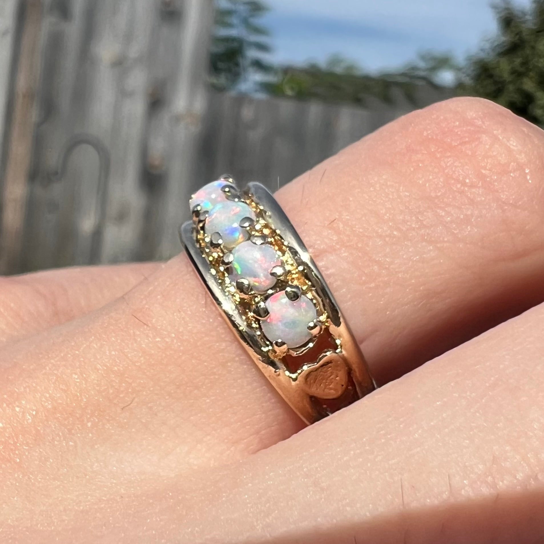 A yellow gold band set with five round cabochon cut opals and heart design accents.