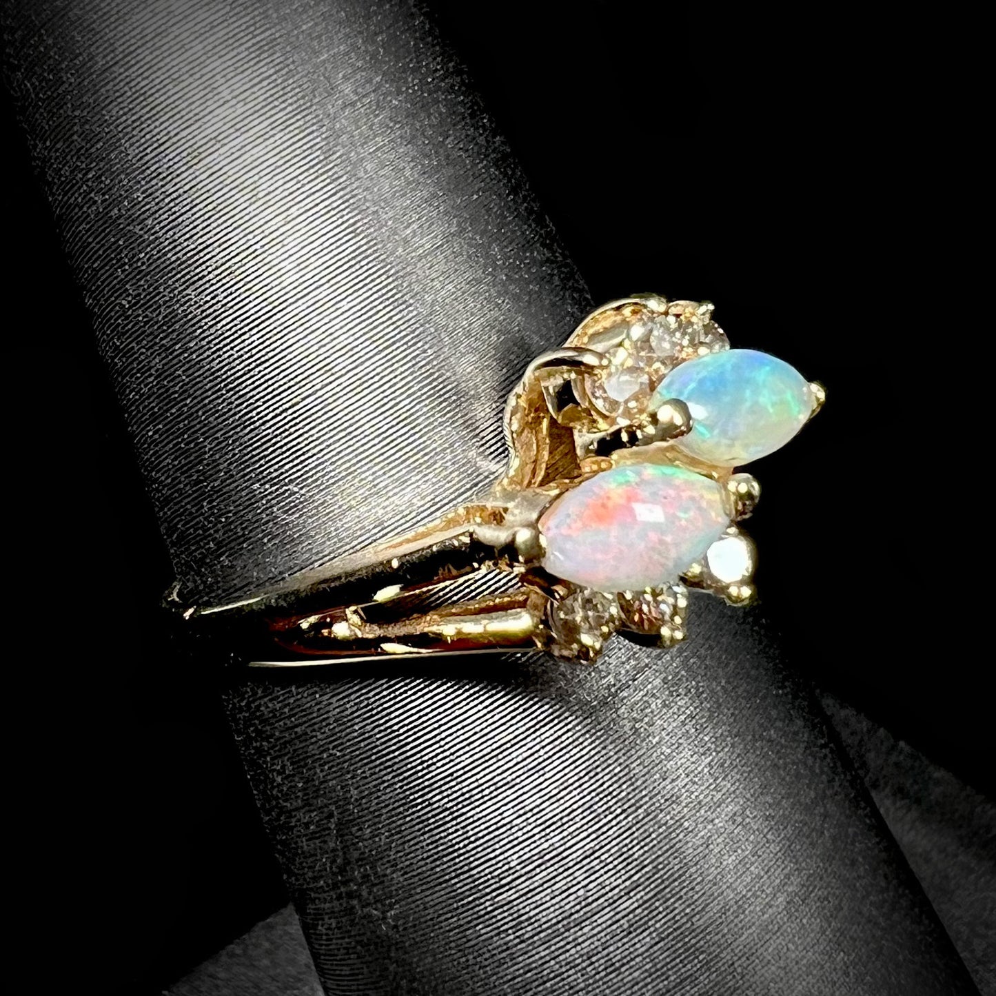 A yellow gold ring mounted with two marquise cut opals and accented with six round diamonds.