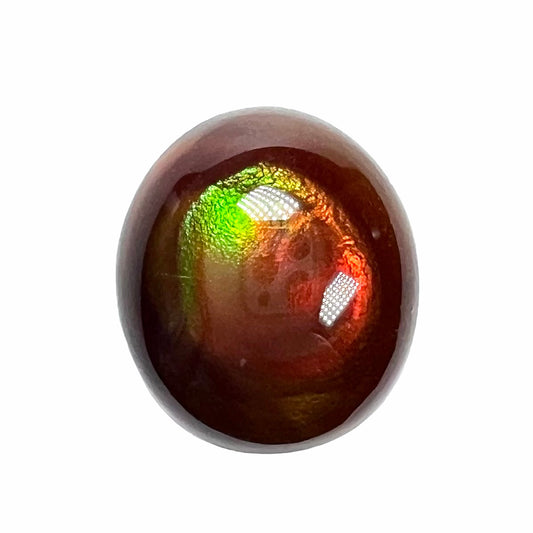 A loose, oval cabochon cut fire agate stone that has red and green colored iridescence.