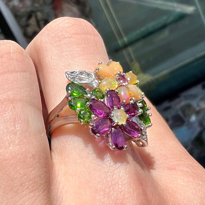 A ladies' gemstone flower design cluster ring set with Ethiopian fire opals, chrome diopsides, rhodolite garnets, and white topaz stones.