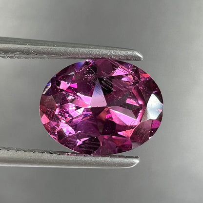 A loose, faceted oval cut purple rhodolite garnet gemstone.