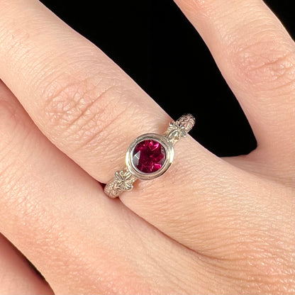 A ladies' sterling silver purple rhodonite garnet solitaire ring.  The shank has an etched floral leaf design.