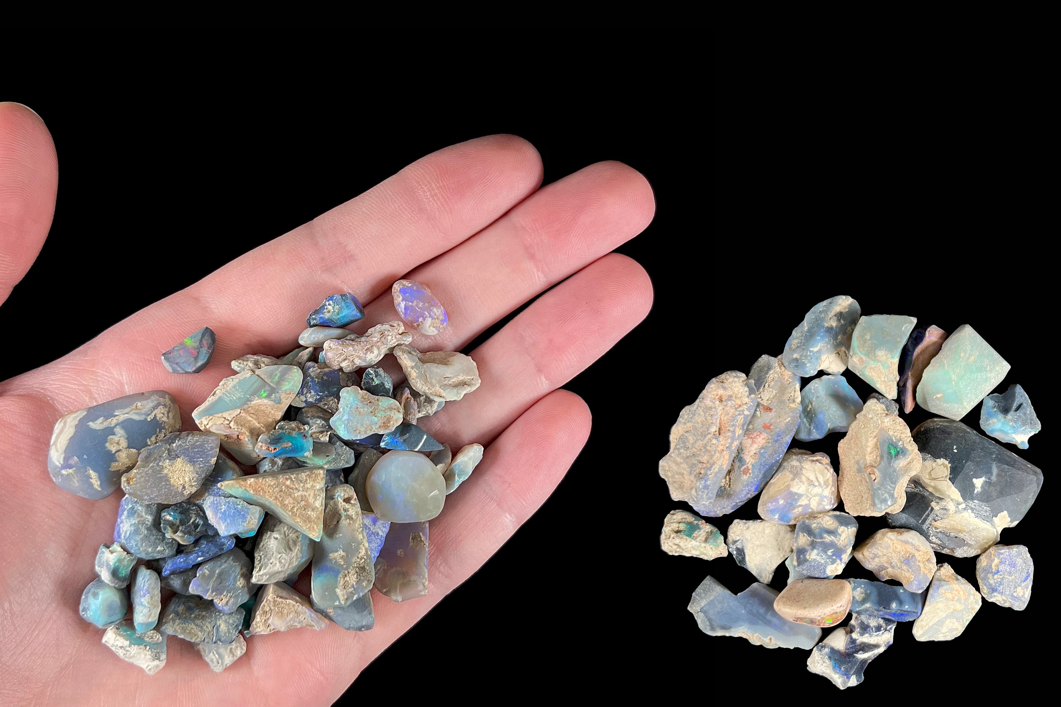 A hand holding a pile of rough opal stones.