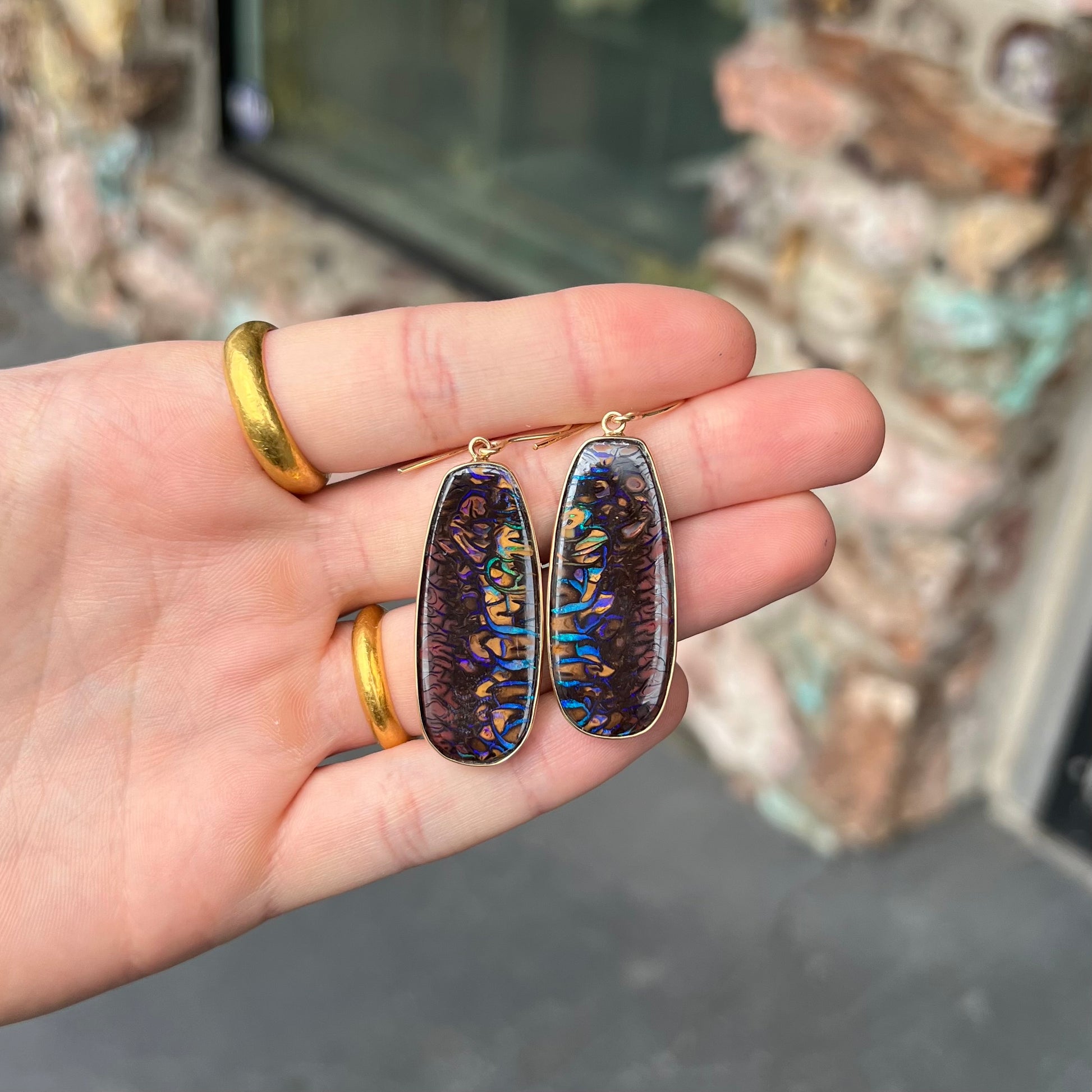 A matched pair of yellow gold patterned boulder opal dangle earrings.  The opals are from Koroit, Australia.