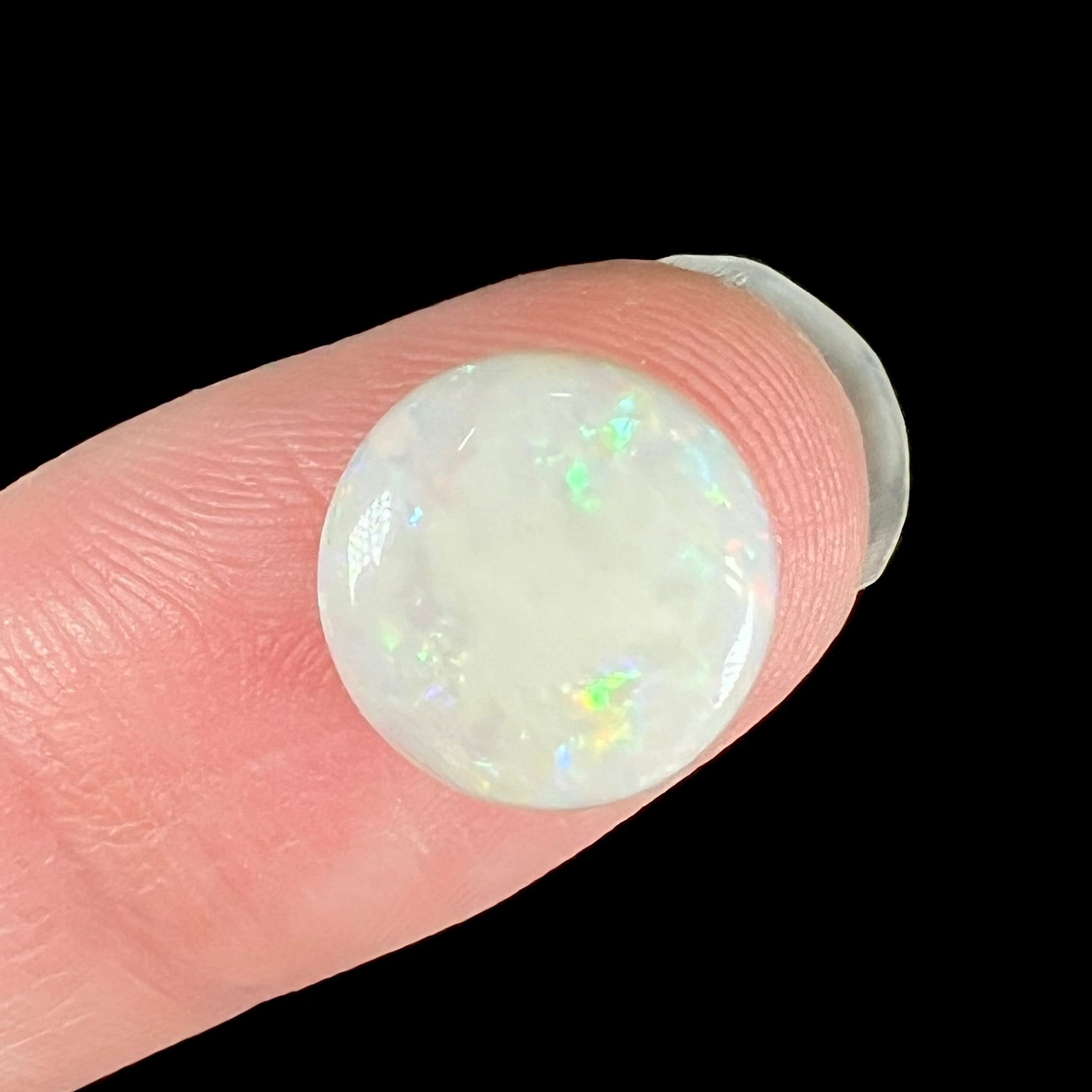 A loose, round cabochon cut white opal from Coober Pedy, Australia.  The opal has green fire.