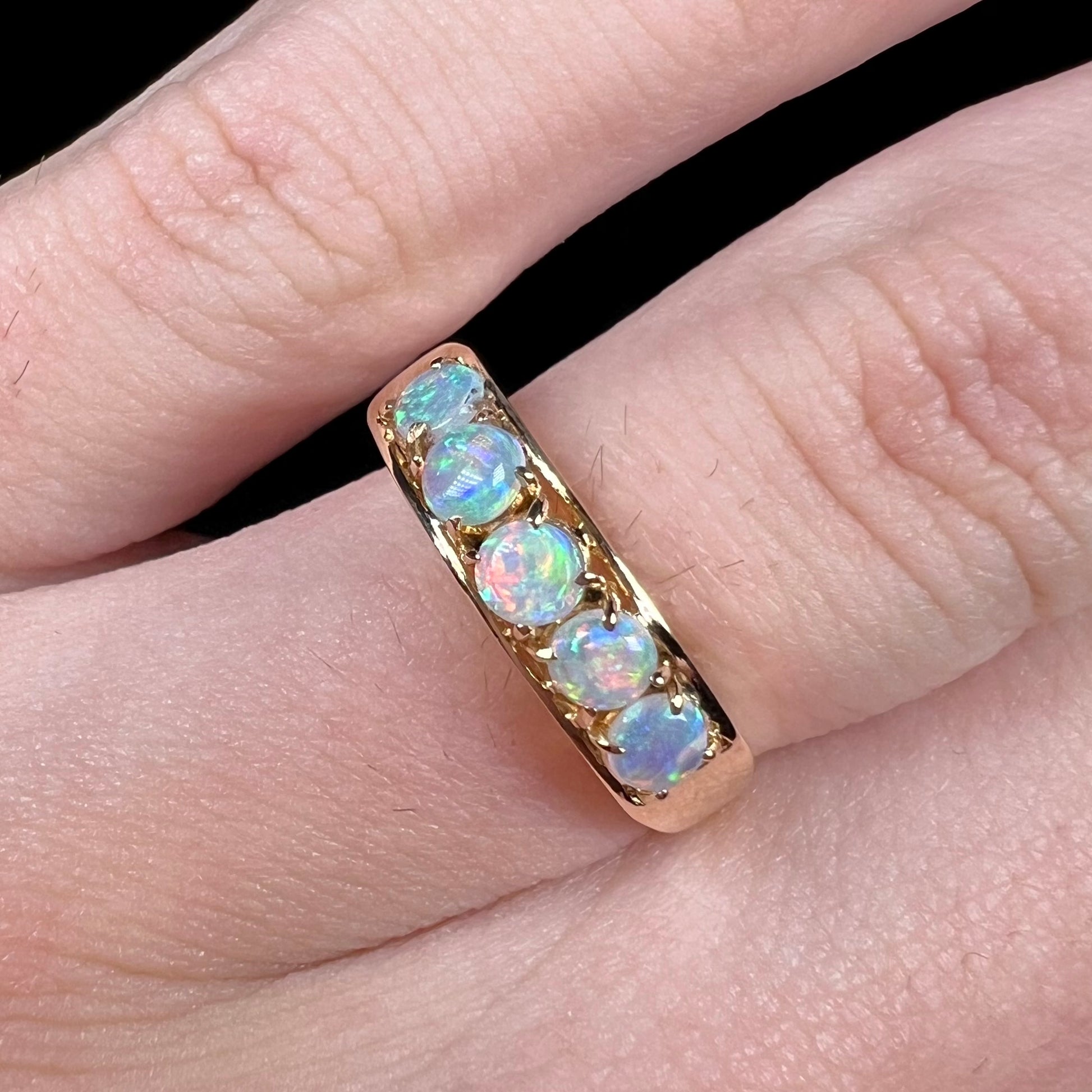 An 18 karat yellow gold line-style filigree ring mounted with five round, cabochon cut Australian crystal opals.