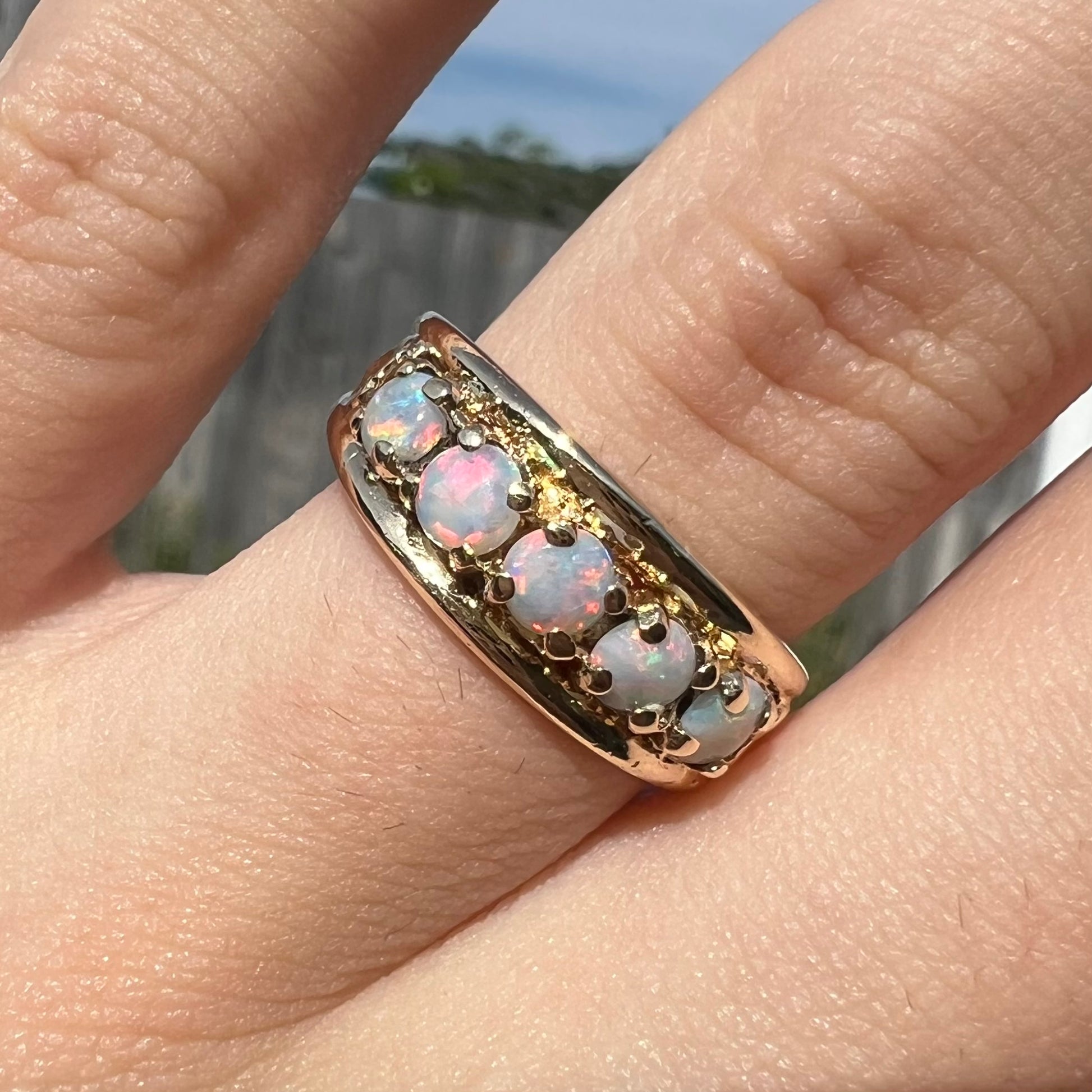 A yellow gold band set with five round cabochon cut opals and heart design accents.