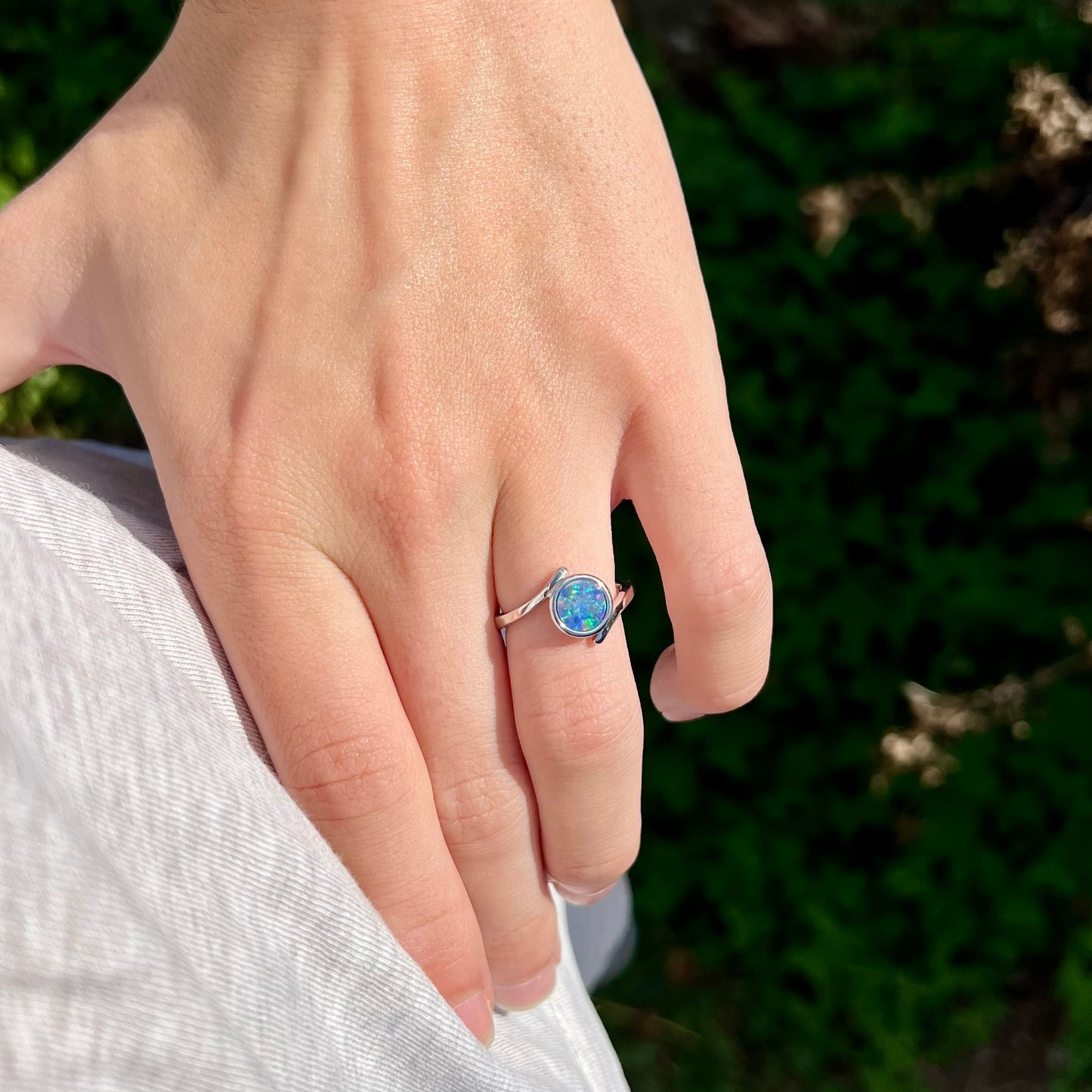 A sterling silver bypass ring bezel-set with a round cut black opal doublet.