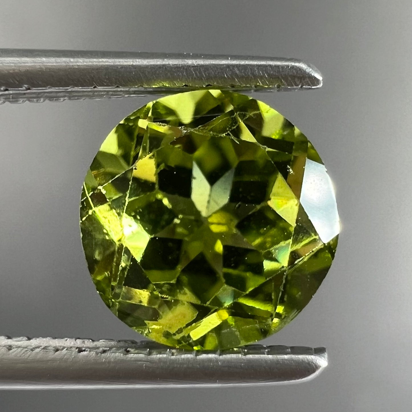 A loose, round brilliant cut peridot gemstone.