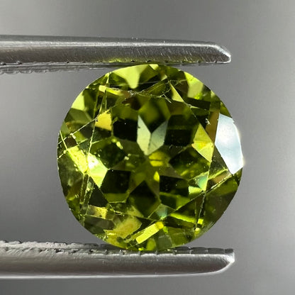 A loose, round brilliant cut peridot gemstone.