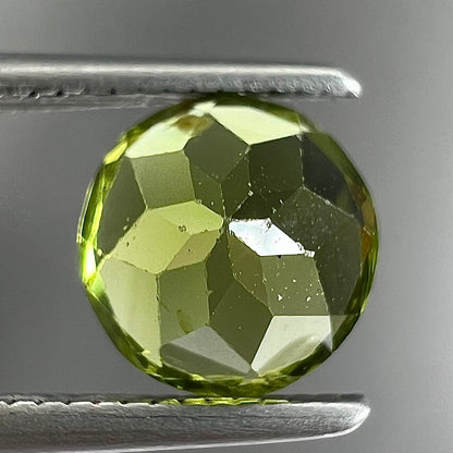 A loose, round brilliant cut peridot gemstone.