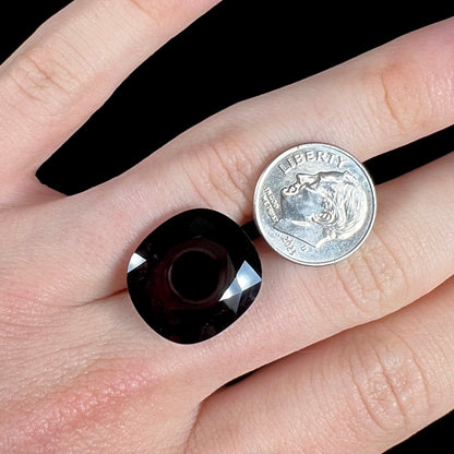 A loose, faceted oval cut rubellite tourmaline gemstone.  The stone is a dark purple red color.