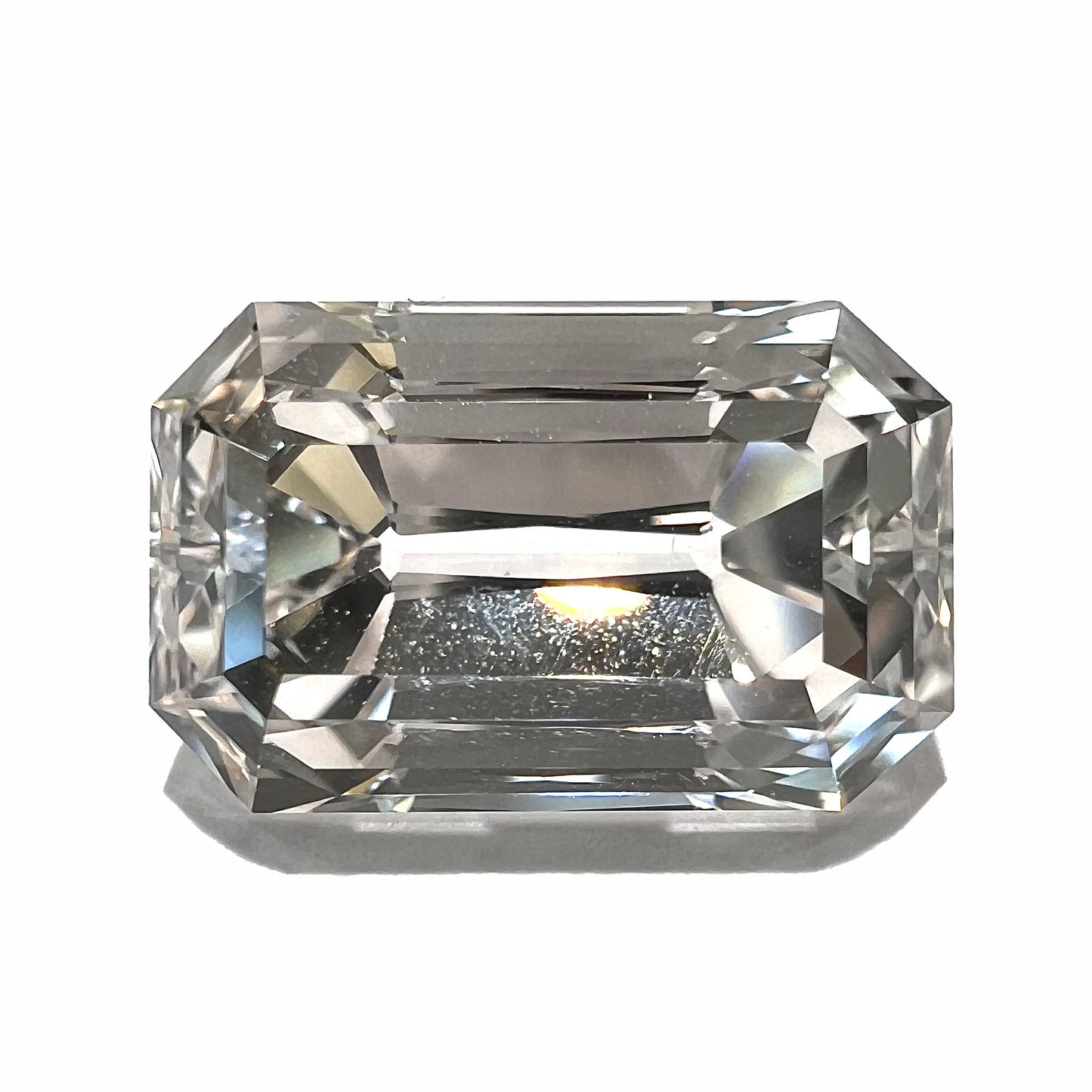 A loose, emerald cut topaz gemstone from Russia.  The stone is a faint pinkish white color.