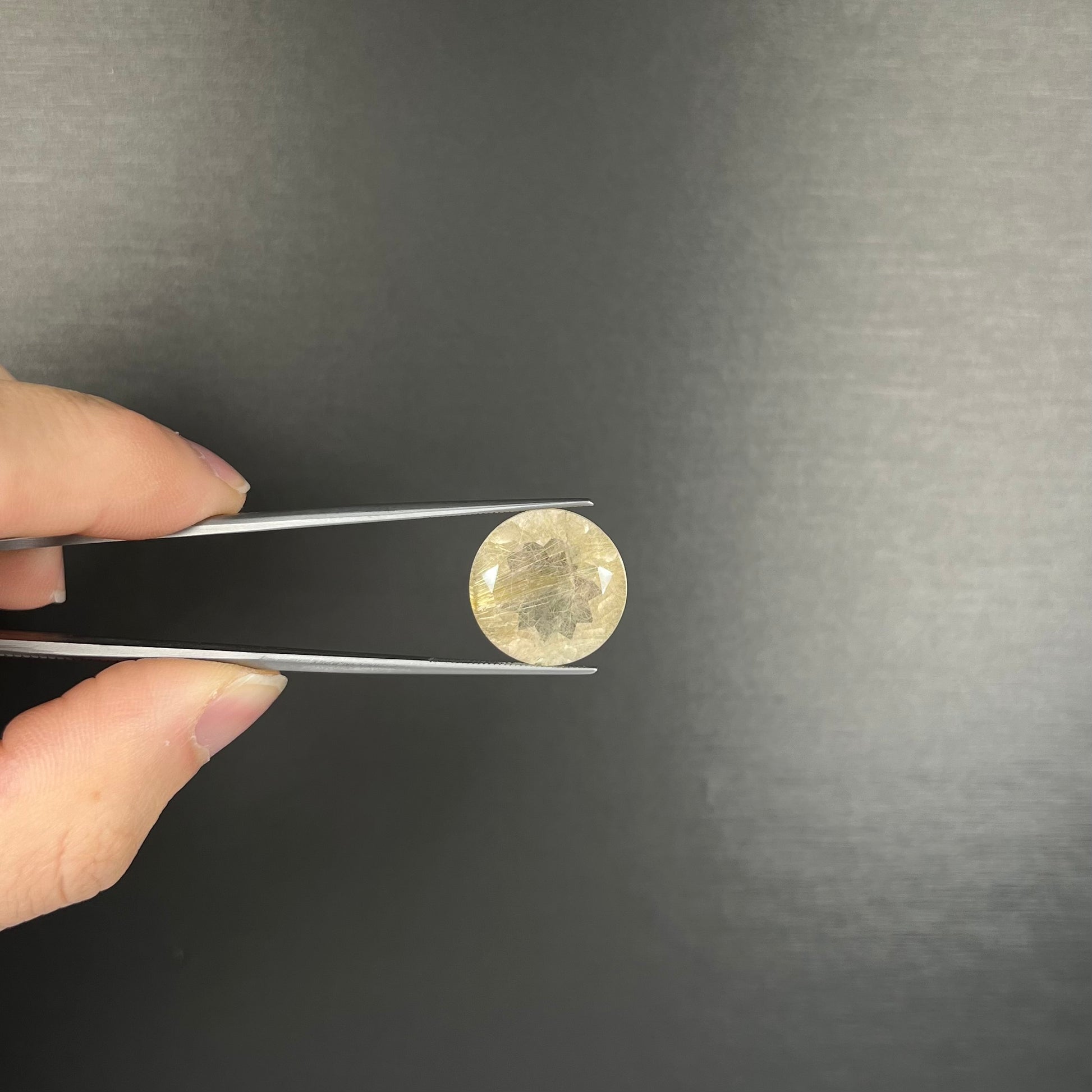 A loose, modified Early American round cut rutilated quartz gemstone.  The rutile inclusions are a golden color.