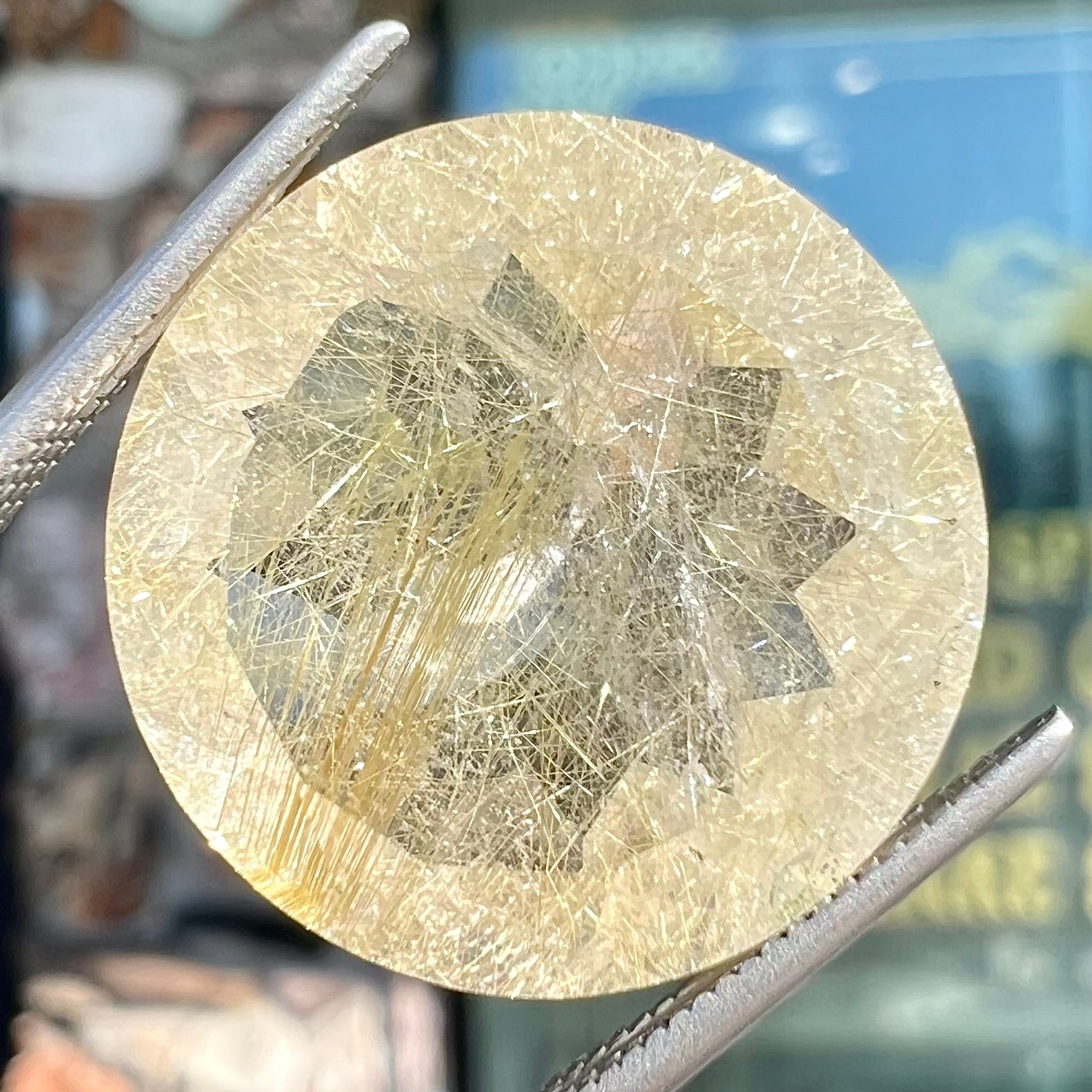 A loose, modified Early American round cut rutilated quartz gemstone.  The rutile inclusions are a golden color.