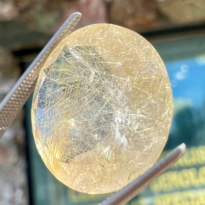 A loose, modified Early American round cut rutilated quartz gemstone.  The rutile inclusions are a golden color.