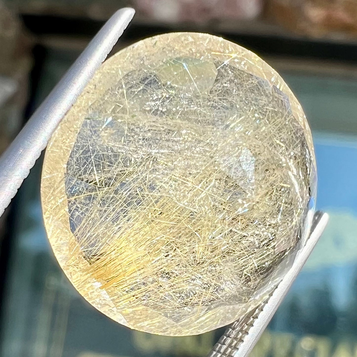 A loose, modified Early American round cut rutilated quartz gemstone.  The rutile inclusions are a golden color.