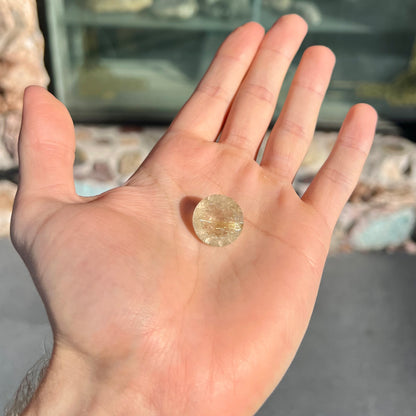 A loose, modified Early American round cut rutilated quartz gemstone.  The rutile inclusions are a golden color.