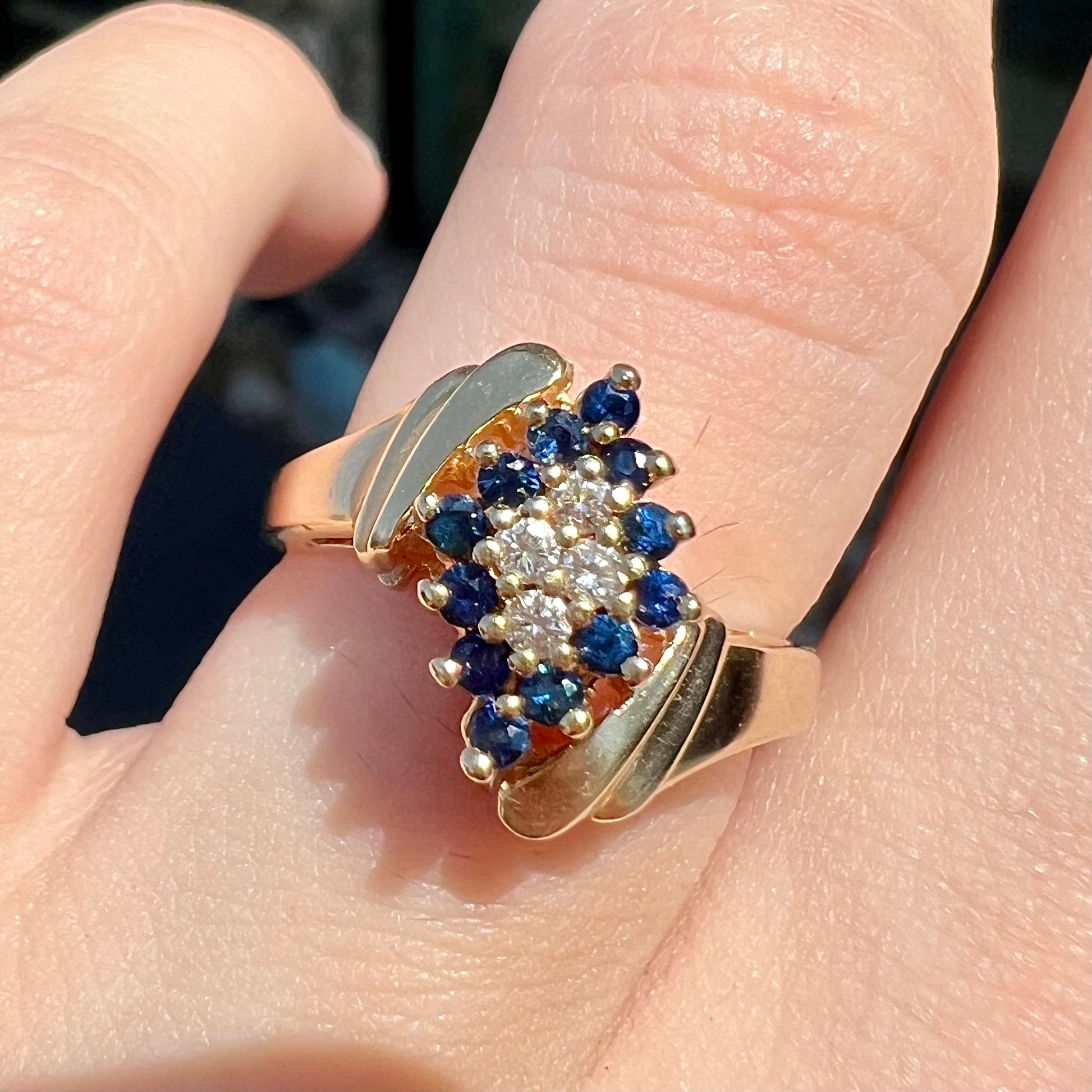 An estate, yellow gold ladies' cluster ring mounted with four round diamonds and twelve round blue sapphires.