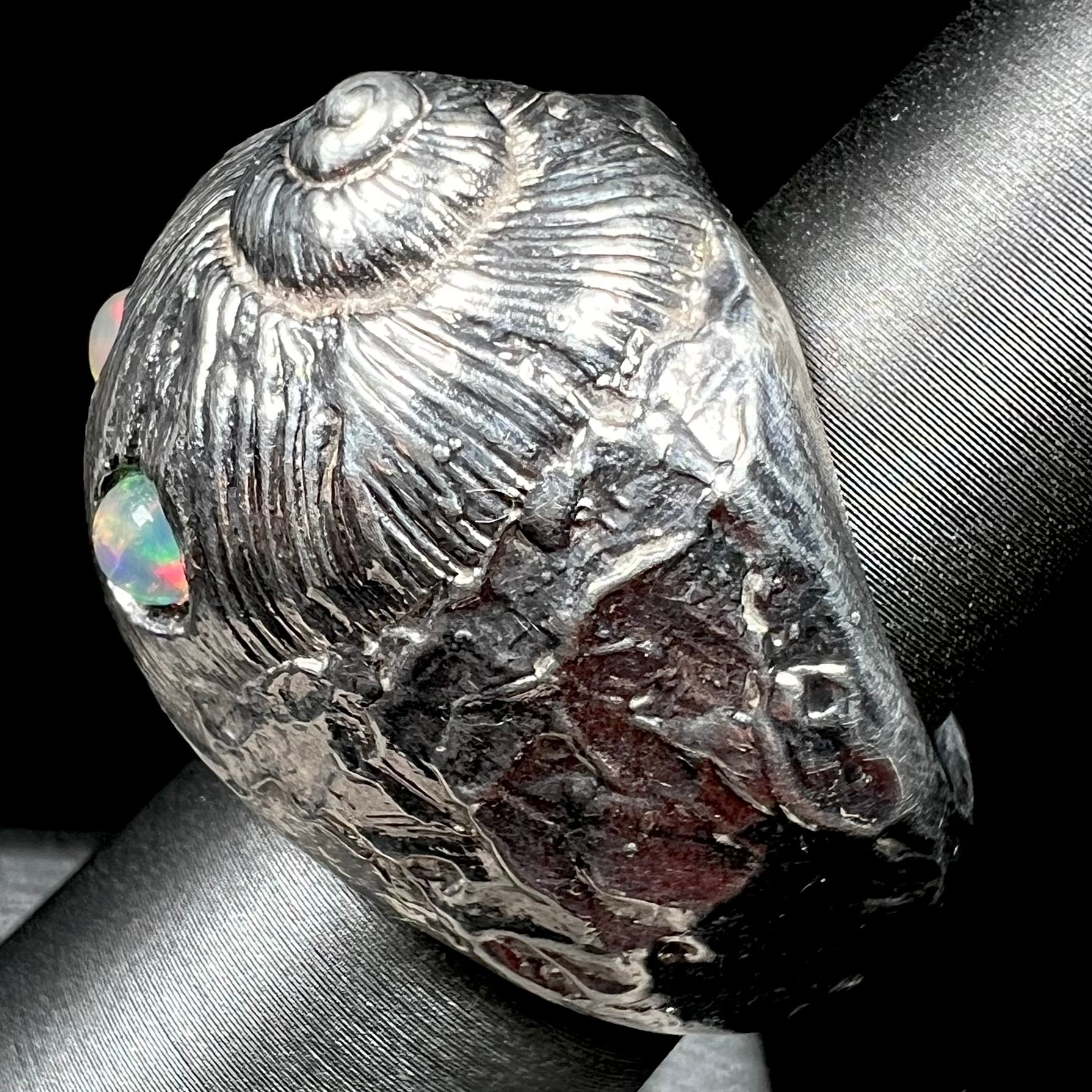 A large, three dimensional sterling silver snail seashell ring set with three round Ethiopian fire opal stones.