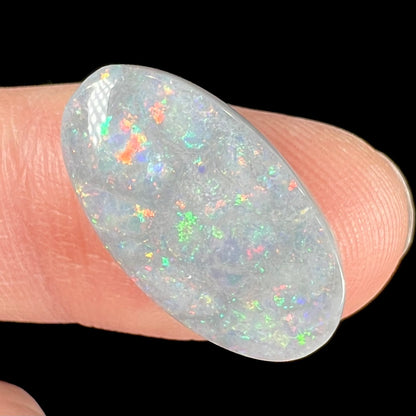 A loose, oval cut semi-black opal stone from Lightning Ridge, Australia.