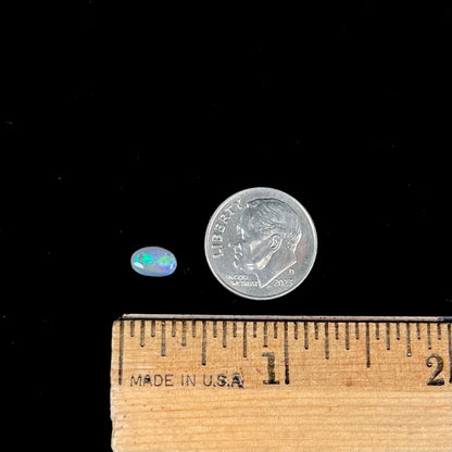 A loose, oval cabochon cut semi-black crystal opal from Lightning Ridge, Australia.