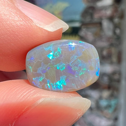 A loose, barrel shaped semi-black opal from Lightning Ridge, Australia.  The opal has blue colors.