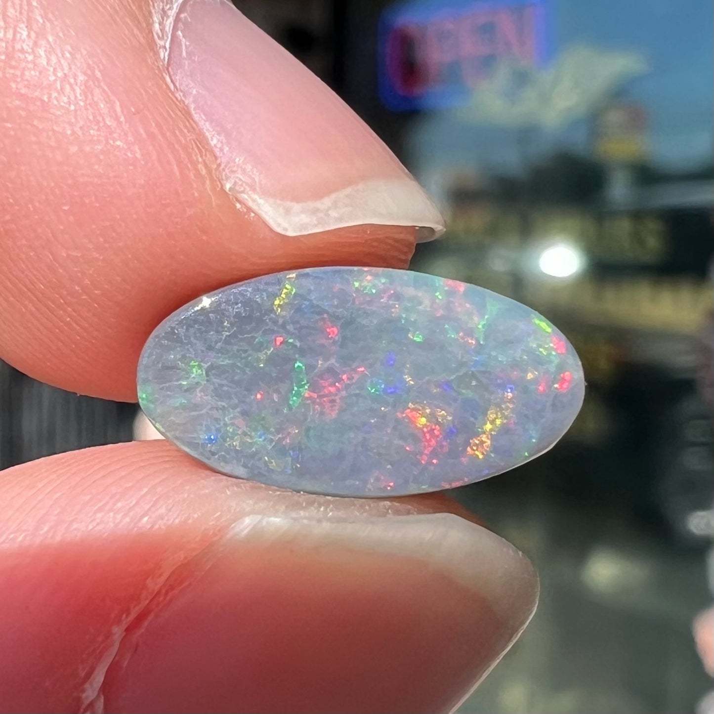 A loose, 3.01 carat, oval cut semi-black opal stone from Lightning Ridge, Australia.  The opal has red colors.