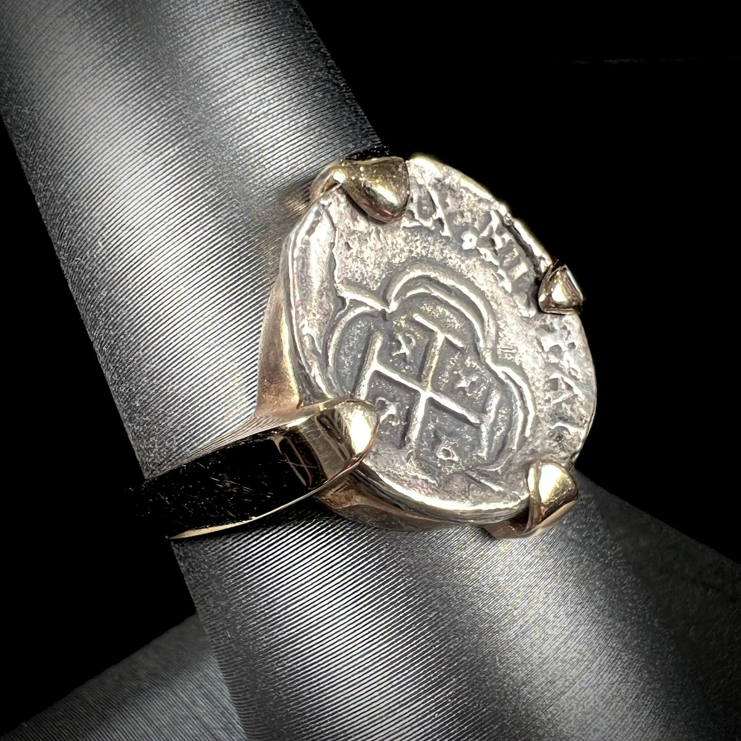 A silver Atocha 1 reale coin replica set in a yellow gold ring.