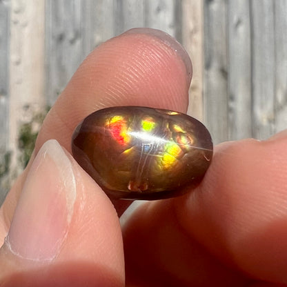 A loose Mexican fire agate cabochon.  The stone has a bright purple and blue iris pattern.