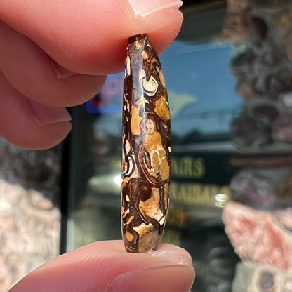 A pear shaped Koroit boulder matrix opal with blue and purple colors in veins.