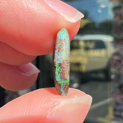 A loose, oval cabochon cut Koroit boulder opal stone.  The opal has a bright green color.