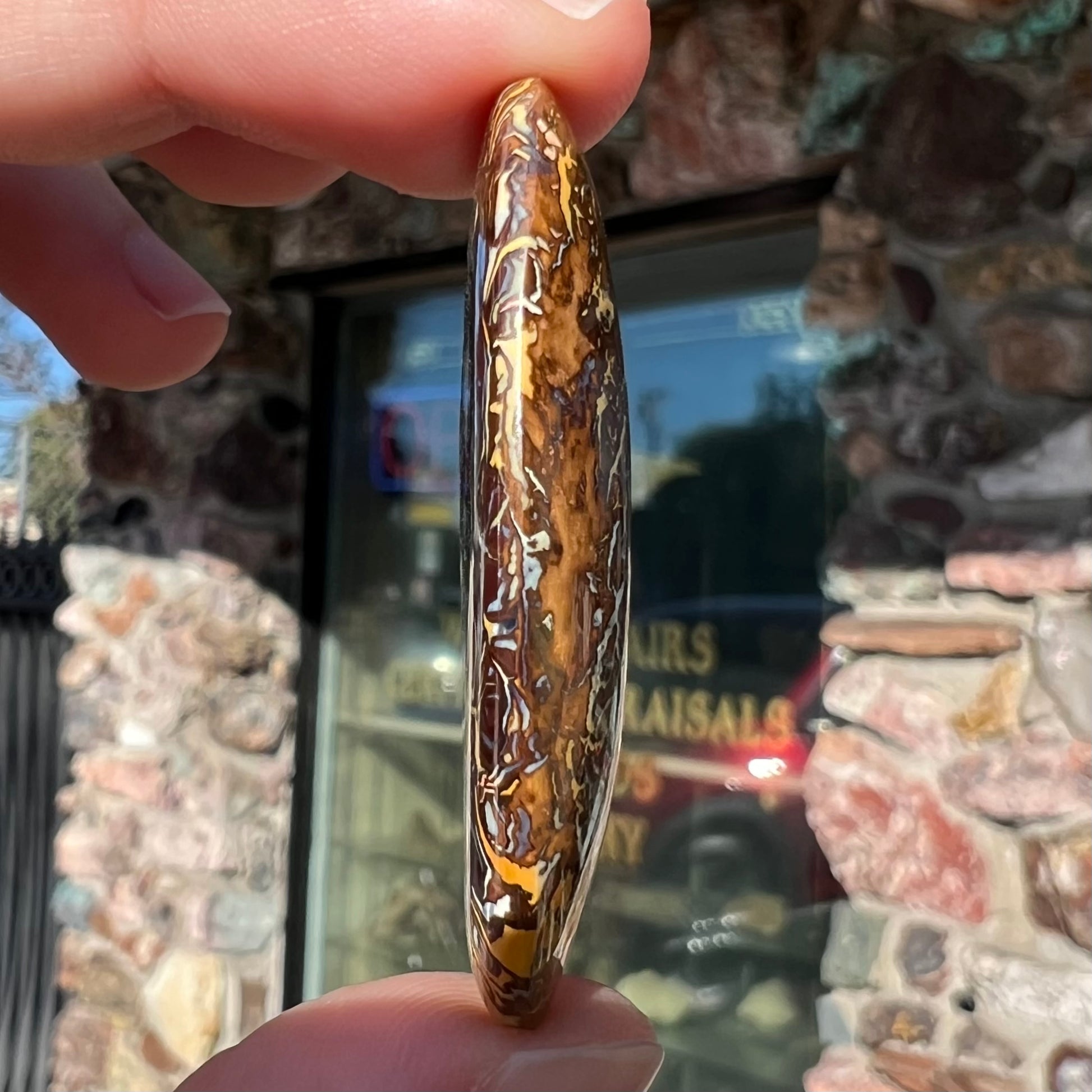 A loose, polished Koroit boulder opal specimen.  The opal has an organic pattern.