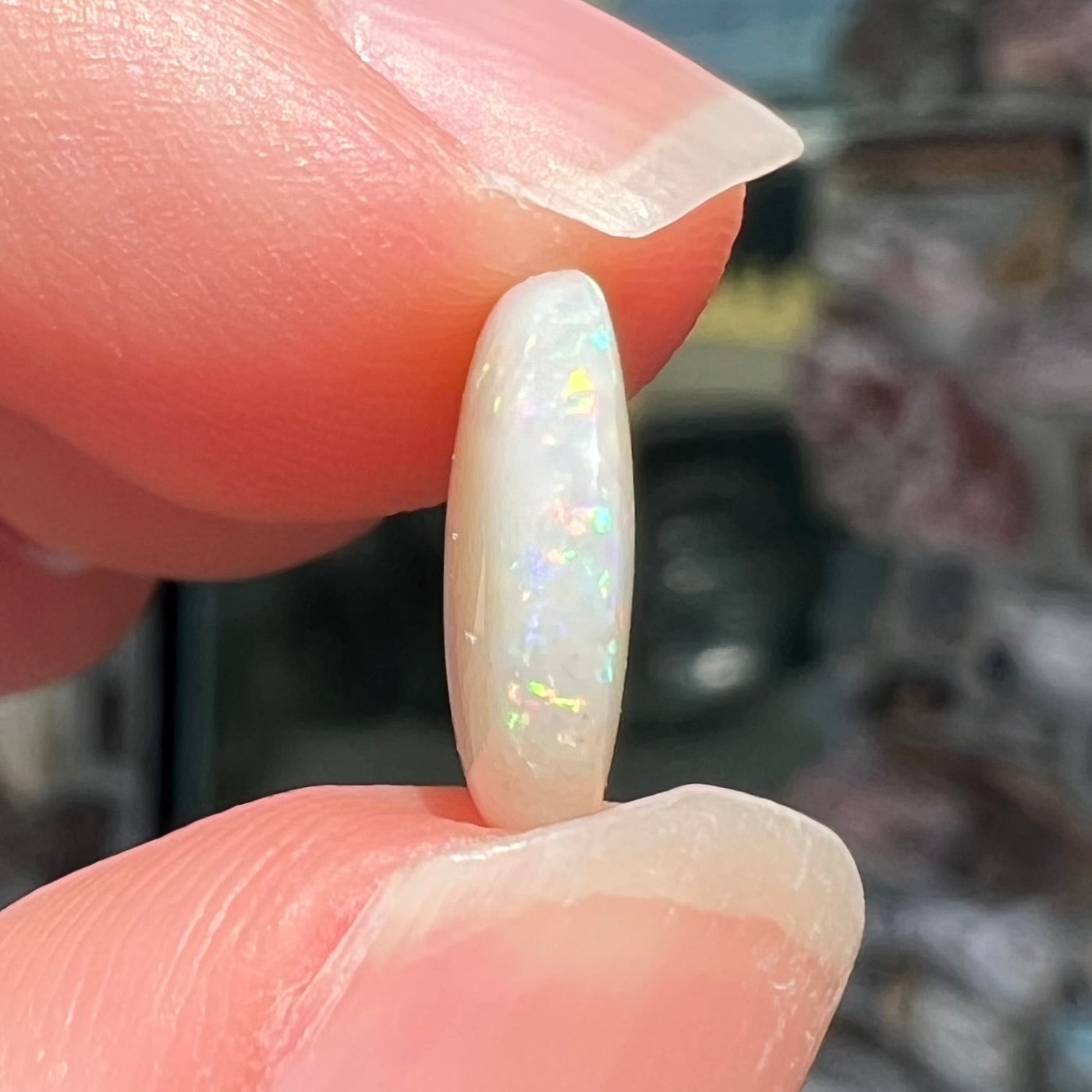 A loose, round cabochon cut white opal from Coober Pedy, Australia.  The opal has green fire.