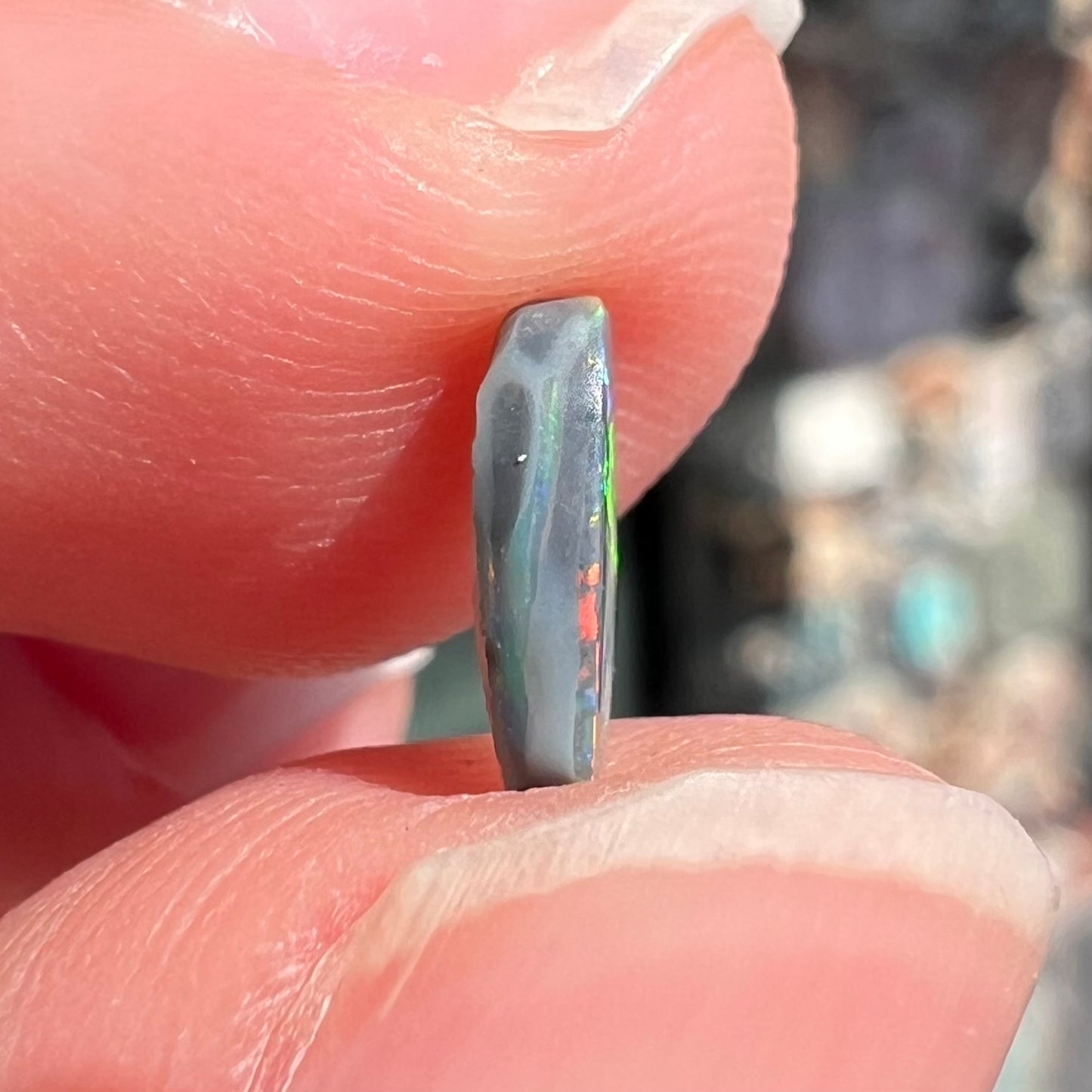 A loose, barrel shaped black opal stone from Lightning Ridge, Australia.