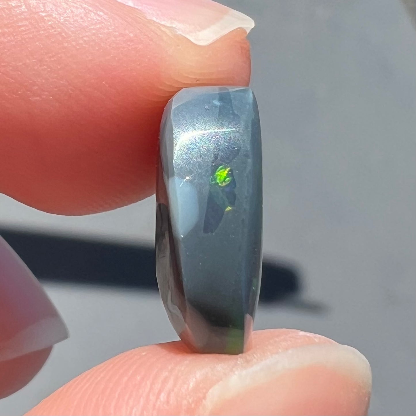 A loose, freeform cut black opal stone from Lightning Ridge, Australia.