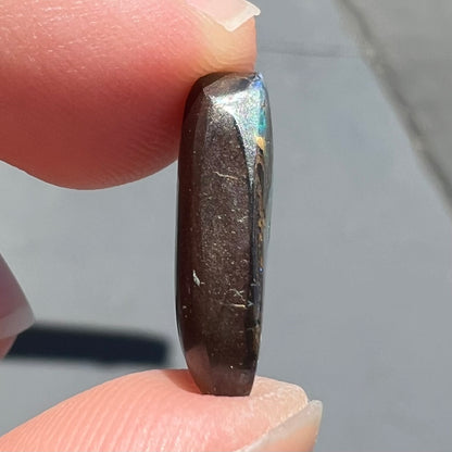 A loose boulder opal stone from Quilpie, Australia.  The opal shines colors of green and orange.