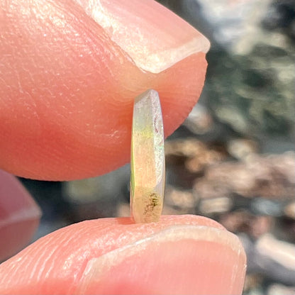 A loose, Australian fire opal chip.  The stone shines red, green, and yellow colors.