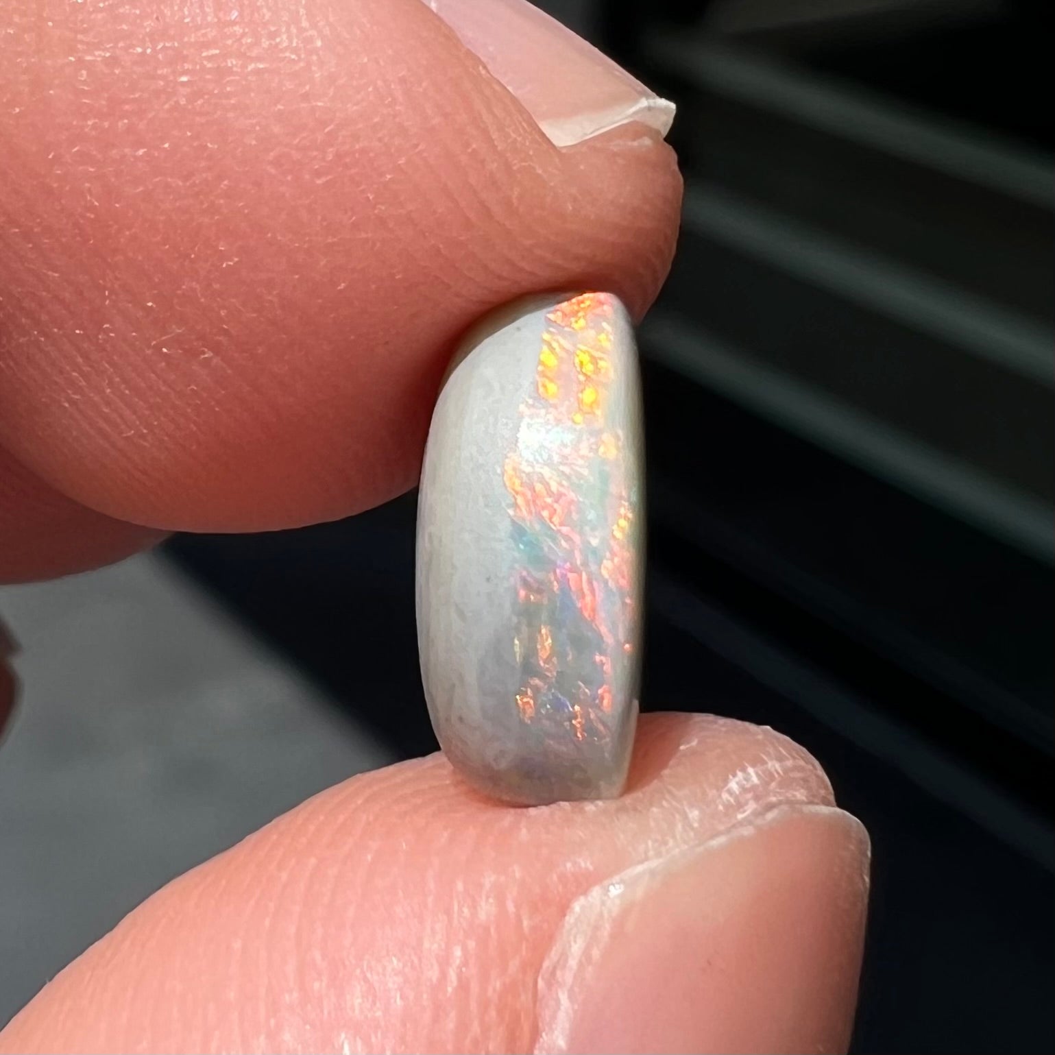 A loose, oval cabochon cut Lightning Ridge light opal stone.